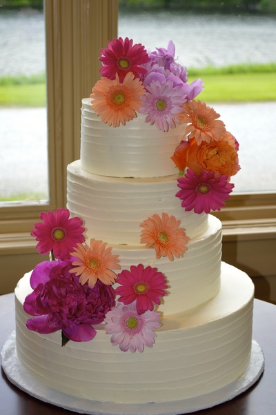 smooth lines buttercream wedding . cake with fresh daisies.  Triangle area.